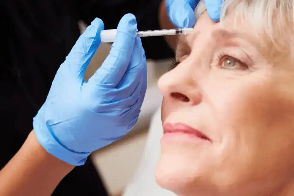 older woman gets injection between her eyebrows