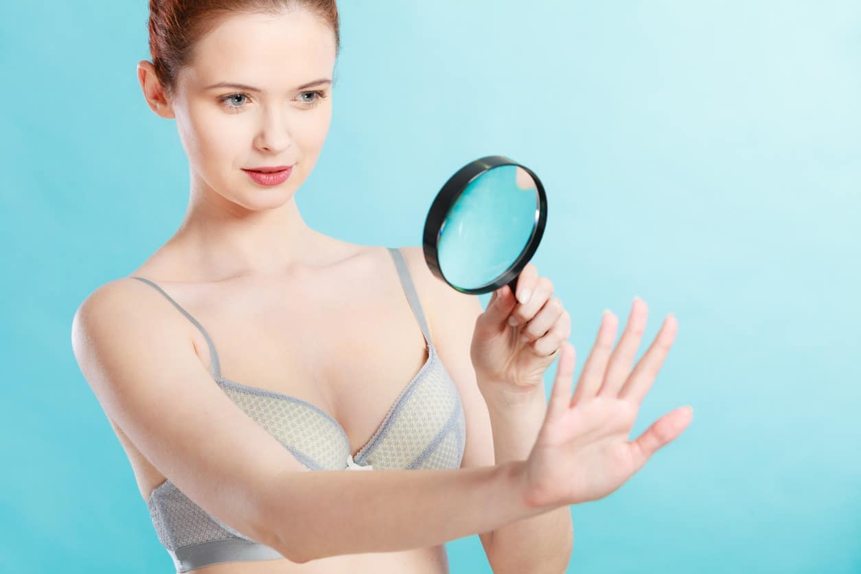 A woman checking her nails with a magnifying glass.