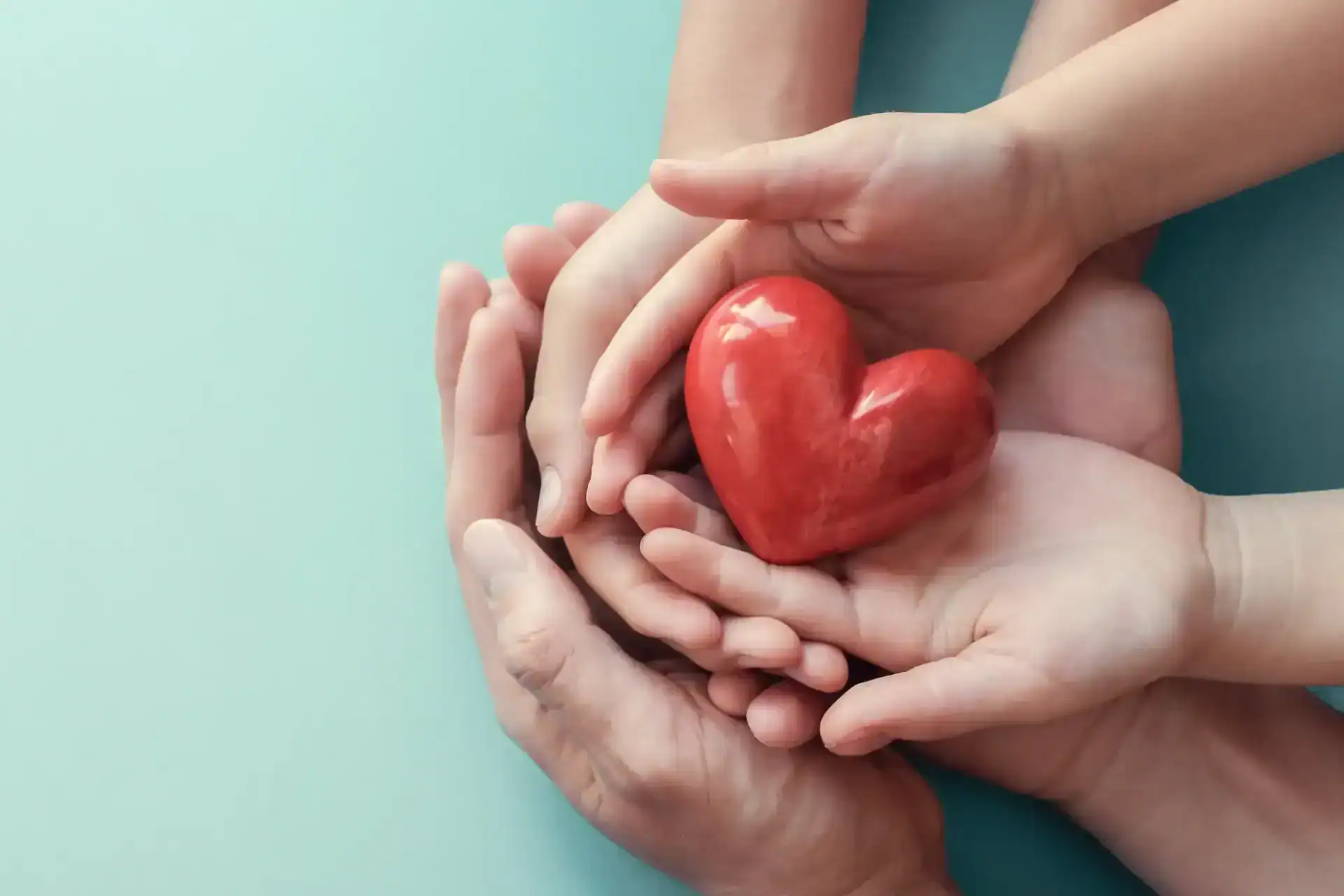 hands of different ages around a red heart, goes with post about the connection between heart disease and certain skin conditions