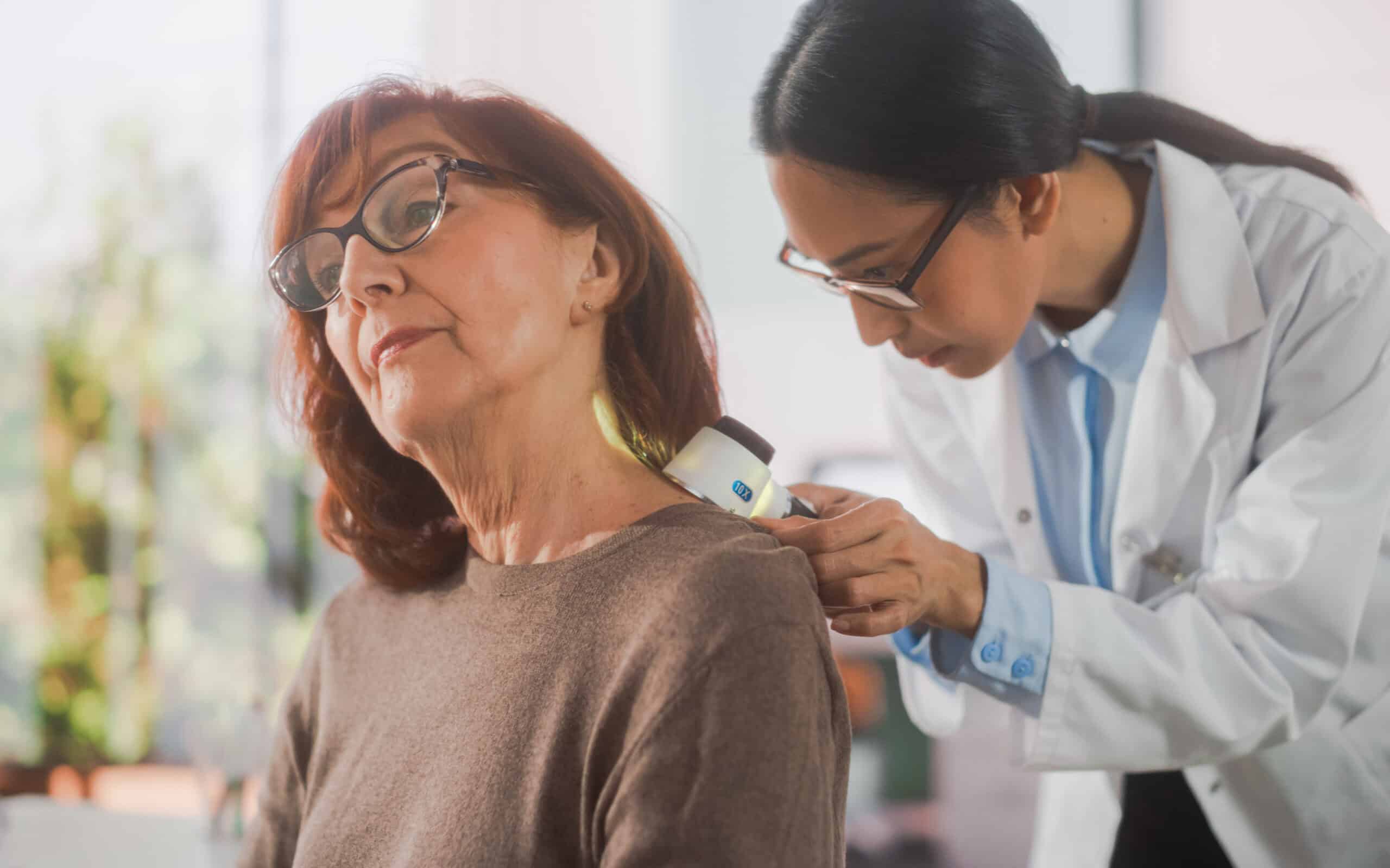 Younger dermatologist works with an older female patient