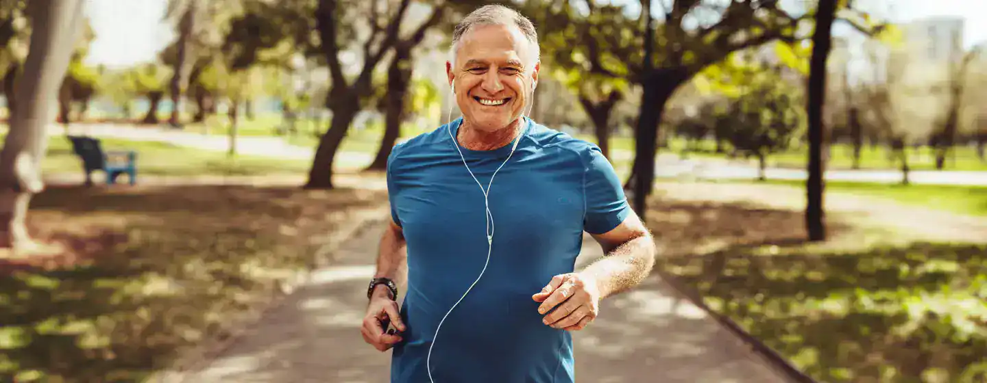 Healthy older man running and enjoying a beautiful day in the park